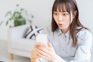 スマホを見る若い女性　驚く
