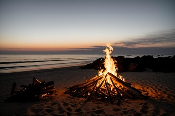 A smoldering bonfire on a beach as the sun begins to rise