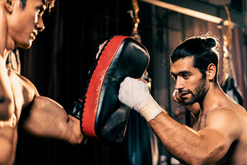 Asian and Caucasian Muay Thai boxer unleash punch in fierce boxing training session, delivering...