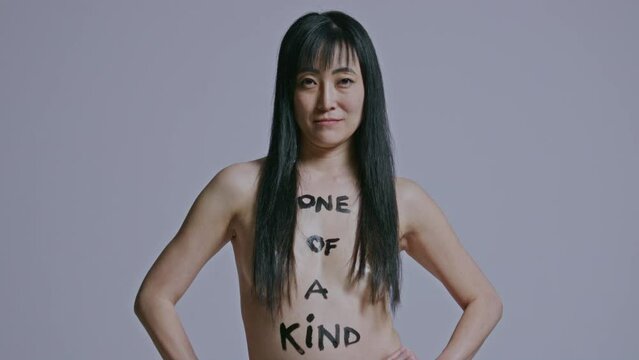 Asian woman stands with her hands on her hips with body paint to on her bare body