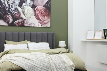 Comfortable bed and painting on wall in bedroom. Stylish interior design