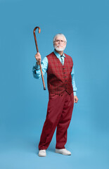 Angry senior man with walking cane on light blue background