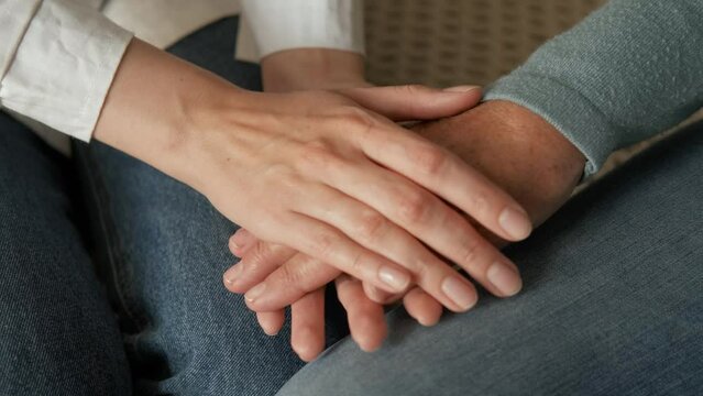 Woman nurse doctor carefully and soothingly stroking the hand of an elderly woman patient close-up