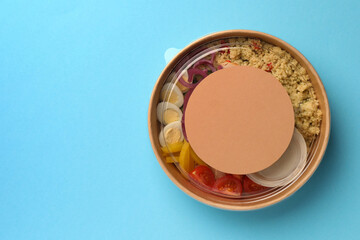 Tasty food in container on light blue background, top view. Space for text