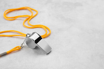 One metal whistle with cord on light grey table. Space for text