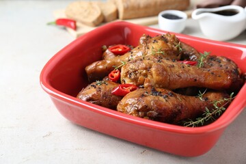 Chicken legs glazed with soy sauce, black sesame, chili pepper and thyme on light table, closeup