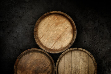 Three wooden barrels near dark textured wall