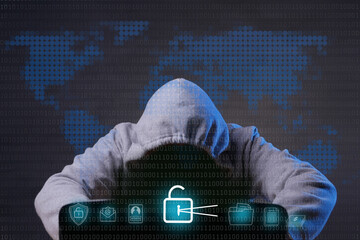 Hacker wearing grey hoodie using laptop computer