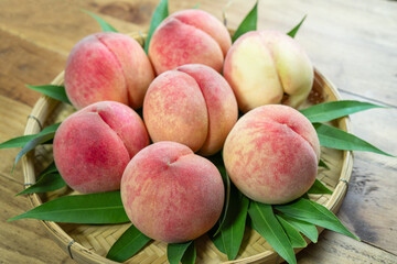 Peaches with leaves on the wooden table, Fresh Peach in wooden basket on wooden Background.