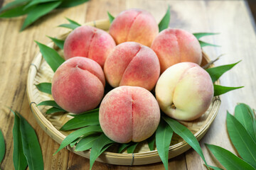 Peaches with leaves on the wooden table, Fresh Peach in wooden basket on wooden Background.