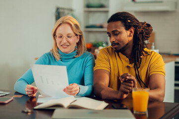 A happy interracial couple is doing paperwork for saving, mortgage loans and taxes at home.