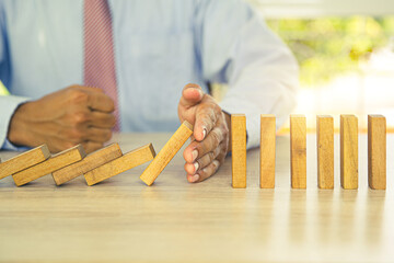Close-up hand prevent wooden block not falling domino concepts of financial risk management and...