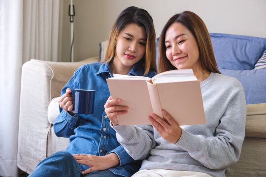 Portrait image of a young couple women enjoyed drinking coffee and reading books together at home