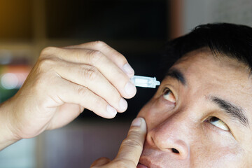 Asian man uses artificial tear lubricant eye drops with his eyes. Concept, Healthcare. Treatment...