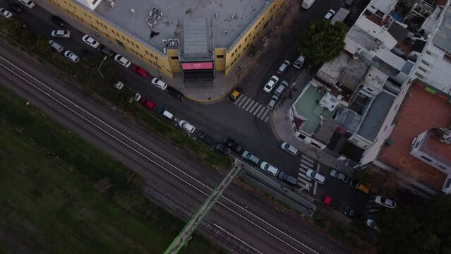 The drone flies over the road running parallel to the railway tracks. Road traffic, parked cars