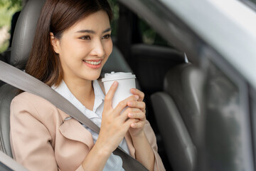 Happy smiling successful young working woman holding take away cup of coffee while sitting in her car