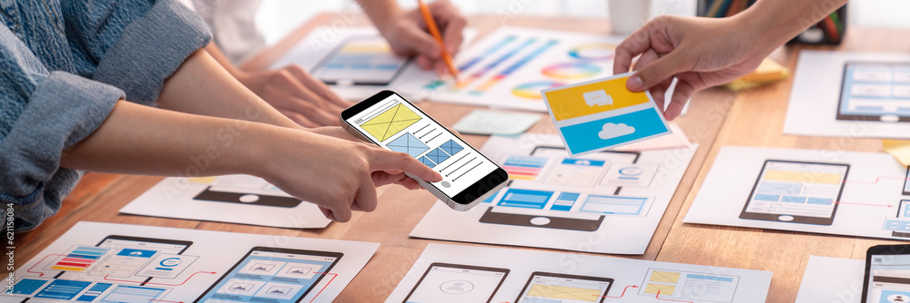 Poster Panorama shot of front-end developer team brainstorming UI and UX designs for mobile app on paper wireframe interface. User interface development team planning for user-friendly UI design. Scrutinize