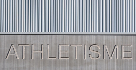 Le mot athlétisme gravé dans un mur en béton