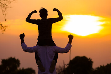 Father carrying son on shoulders on field against sky