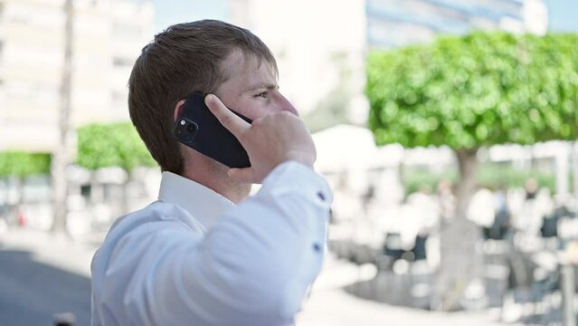 Young caucasian man talking on smartphone at coffee shop terrace