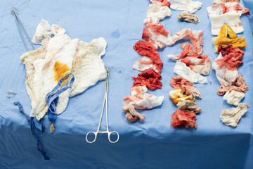 White gauzes for blood lining on blue non-germ cloth  background.Messy bloody gauze bandages on the...