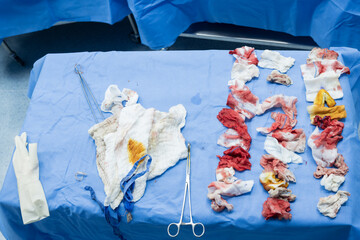 White gauzes for blood lining on blue non-germ cloth  background.Messy bloody gauze bandages on the...
