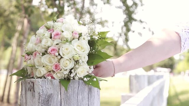 Bride in white dress takes wedding bouquet of flowers on a walk