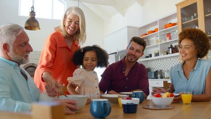 Multi-generation family at home enjoying breakfast sitting around table together - shot in slow motion - Powered by Adobe