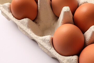 Сhicken eggs lie in a cardboard tray on a white background, top view