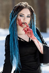 girl in black with blue hair dreadlocks with bloody face