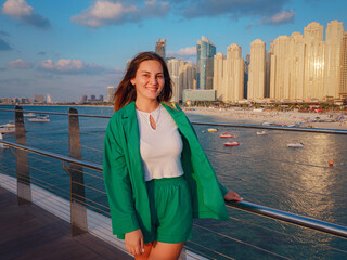 young woman in green suit walks streets of Dubai, Dubai Marina district Blue water Island. United...