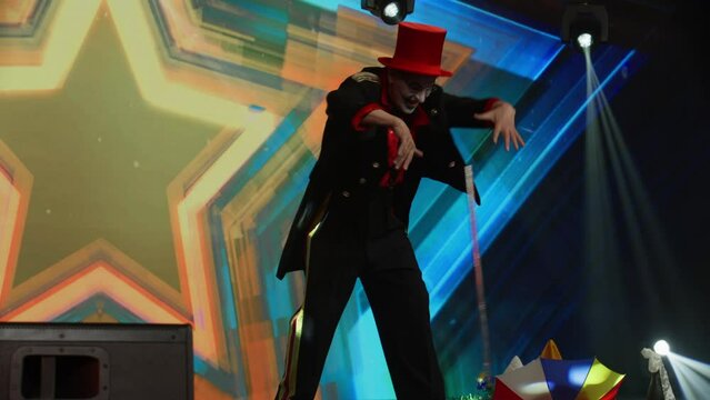 Creepy clown mime showing magic tricks with a flying stick on stage during talent show audition. Broadcast television style TV entertainment program 