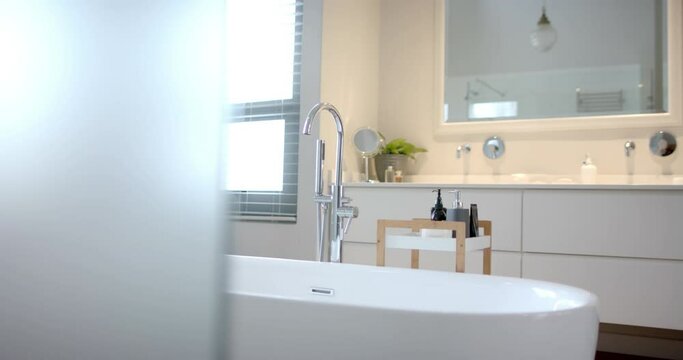Close up of sunny white bathroom with freestanding bathtub, slow motion