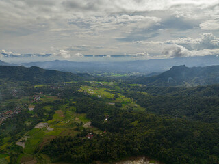 Fototapeta na wymiar Aerial drone of mountains with green forests and agricultural land with farm plantations. Bukittinggi, Sumatra. Indonesia.
