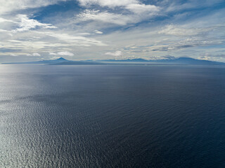 Aerial view of blue sea with island and blue sky with clouds. Flight over the sea. Indonesia.