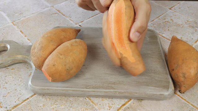 personne &eacute;pluchant une patate douce