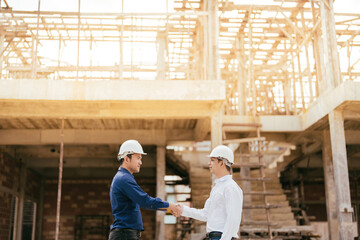 2 Asian male engineers are master technicians and supervisors. in construction design holding hands working together for success about the architecture industry Wear helmets and uniforms.