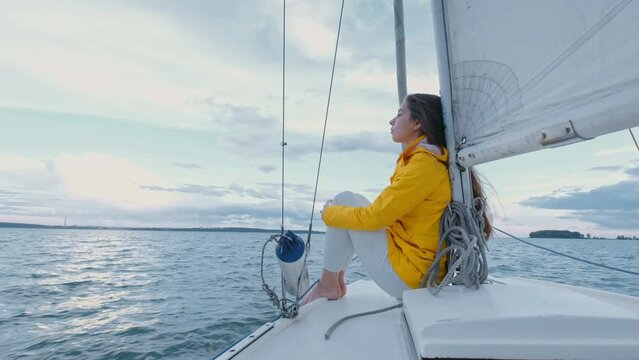 Lonely Woman relax on floating yacht. Alone caucasian beautiful girl standing on the yacht deck and looking at horizon. Travel concept, holiday, sea waves and sailing