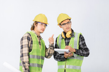 Two handsome young Asian engineers in light green coats and yellow hats inspecting work, hand holding radios and check papers. check paper confident gesture on white background