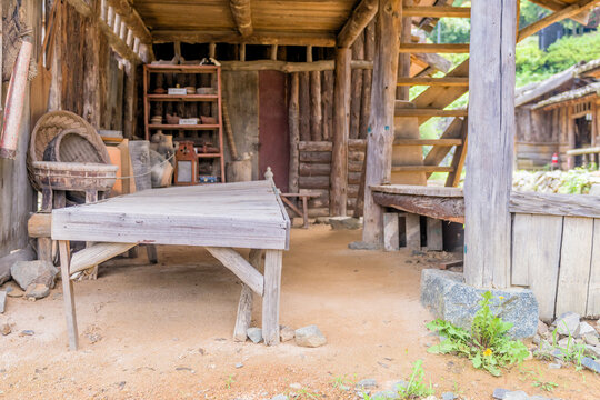 Old uneven wooden table under open outdoor storage area.