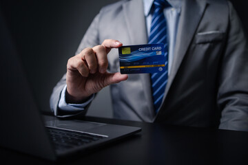 Man in suit with credit card, businessman hold credit card, using credit card to pay for goods and services in store, online shopping on website and paying by credit card. Online shopping concept.