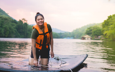A tourist chubby girl wear life jacket smiling on pontoon in Kanchanaburi river with natural therapy relax in vacation holiday in thailand concept