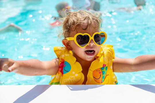 The child swims in the pool in a vest. Selective focus.