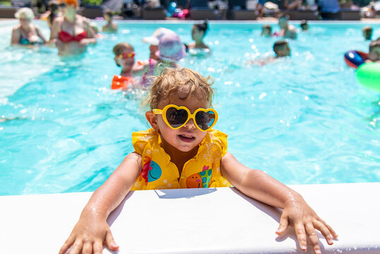 The child swims in the pool in a vest. Selective focus.