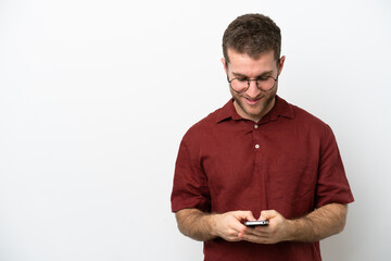 Young caucasian man isolated on white background sending a message with the mobile