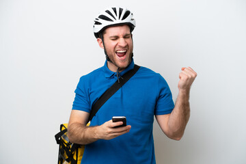 Young caucasian man with thermal backpack isolated on white background with phone in victory position