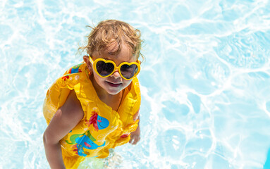Naklejka premium The child swims in the pool in a vest. Selective focus.