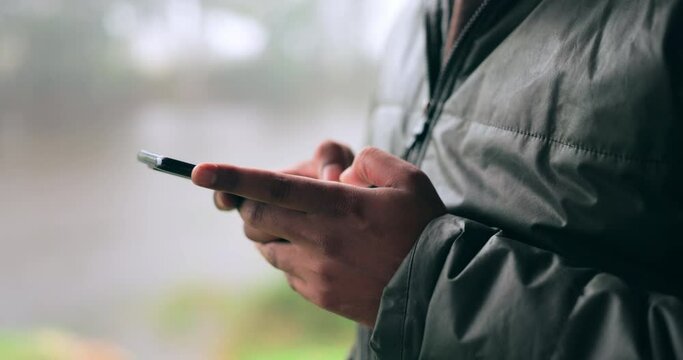 Hands, phone and communication with a person on a blurred background outdoor on an overcast day. Mobile, contact and social media with an adult typing a text message in the rain during winter