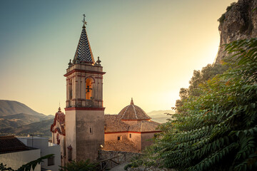 View of the tower and dome of the Church of Santa Maria de la Mesa, at dawn in a natural environment of the town of Zahara de la Sierra, Cadiz, Andalusia, Spain