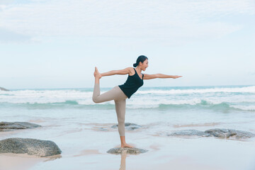 A woman gracefully practices yoga at the beach, embracing the soothing ambiance and finding inner peace amidst the waves.